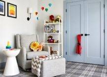 Transitional gray boy's nursery features powder blue double closet doors with black handles, white toy shelf, gray wingback nursery glider, nursery hot air balloons mobile and gray plaid carpeting.