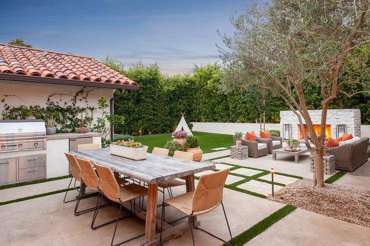 Transitional outdoor patio furnished with a natural woven dining set and a backyard kitchen with a concrete countertop.