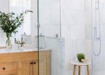 Bathroom features a marble walk in shower with a marble and teak accent table and honed marble hexagon shower floor tiles.