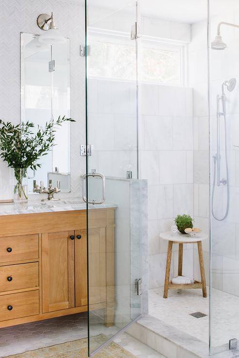 Bathroom features a marble walk in shower with a marble and teak accent table and honed marble hexagon shower floor tiles.