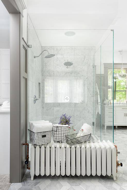 Bathroom features a marble shower with his and hers shower heads, a clear partition and a vintage radiator.