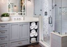 grey bathroom cabinetry with hardwood floor walk in shower folded white towels in open cabinetry