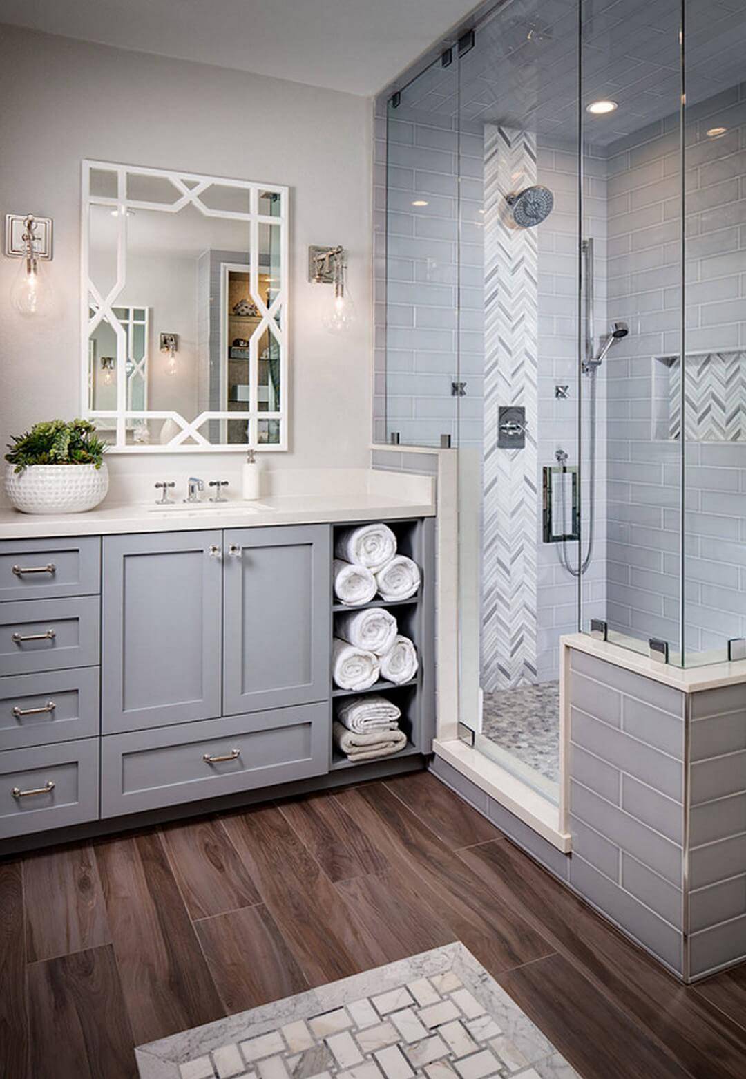 grey bathroom cabinetry with hardwood floor walk in shower folded white towels in open cabinetry
