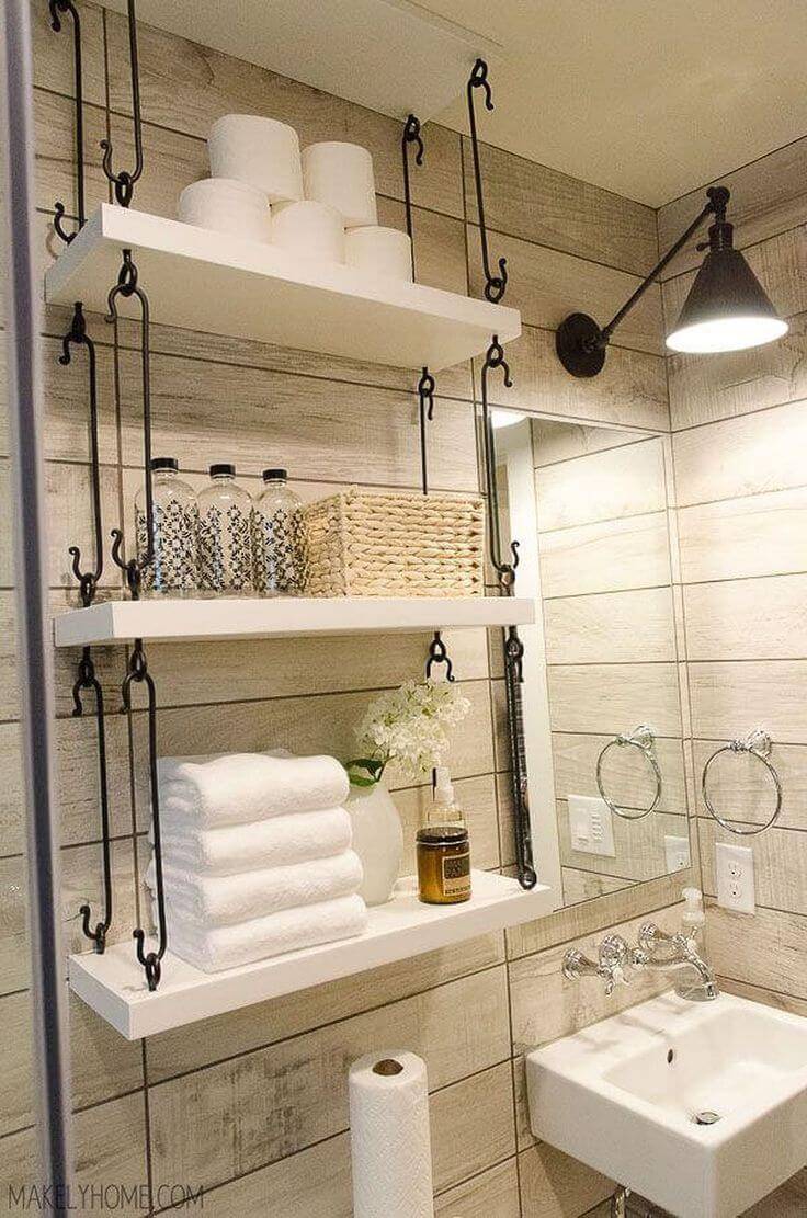white hanging shelves with black wrought iron hooks toilet paper on top shelf over toilet