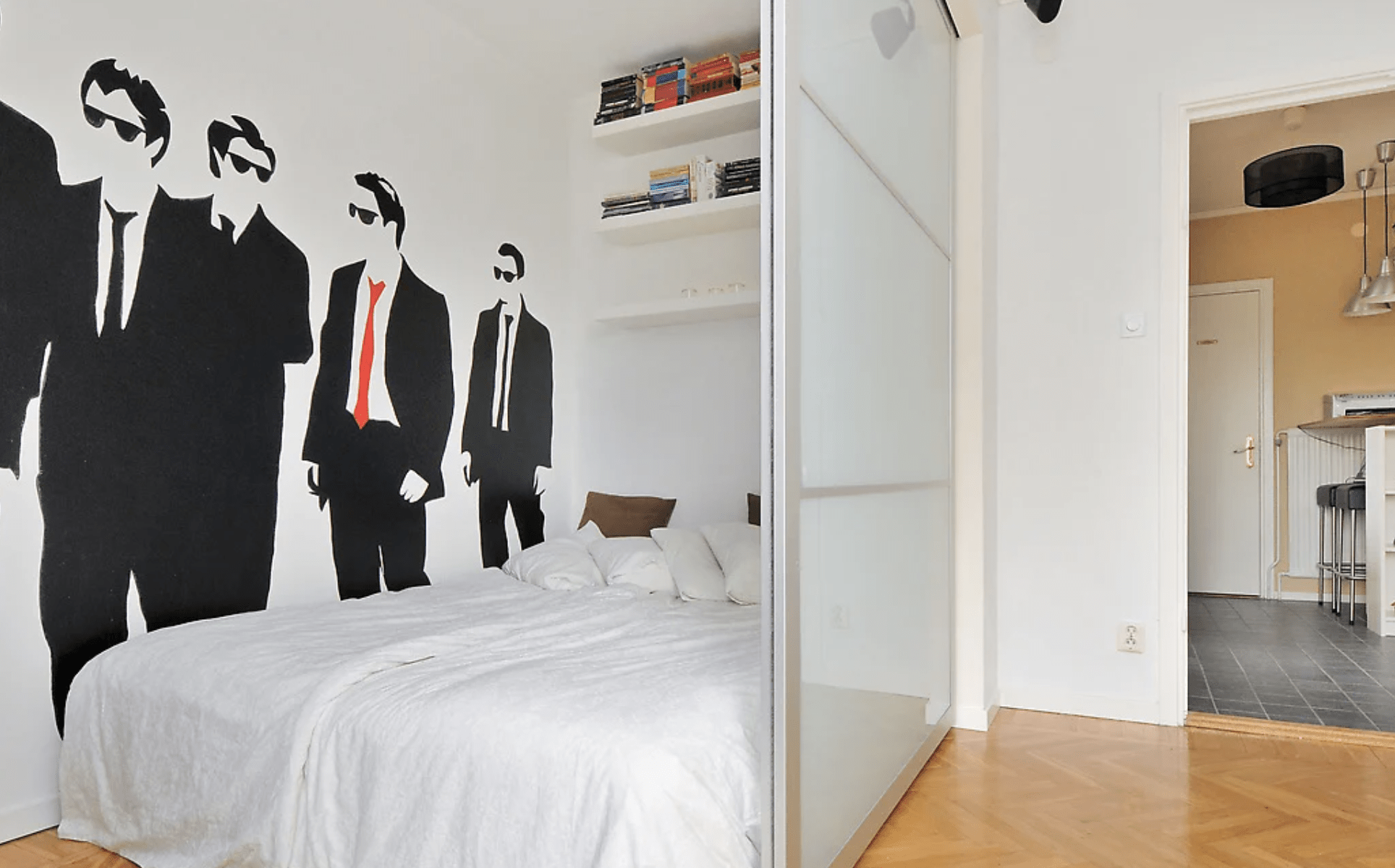 small apartment with ikea frosted glass doors separating off bed from living area silhouette of suited men with sunglasses on wall red tie