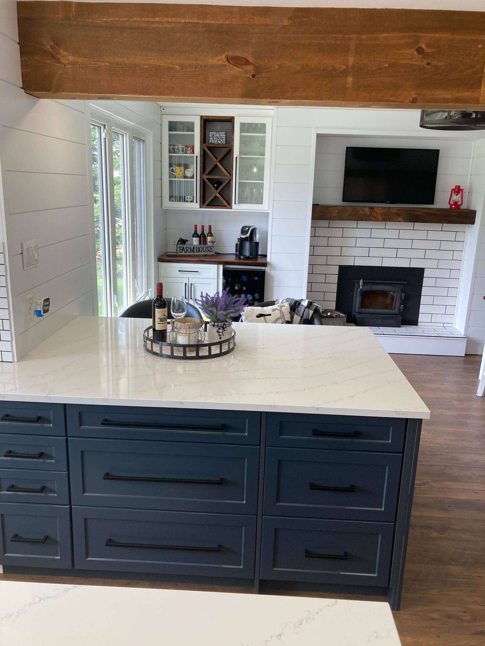 quartz kitchen countertops on blue cabinets with wooden beam overhead