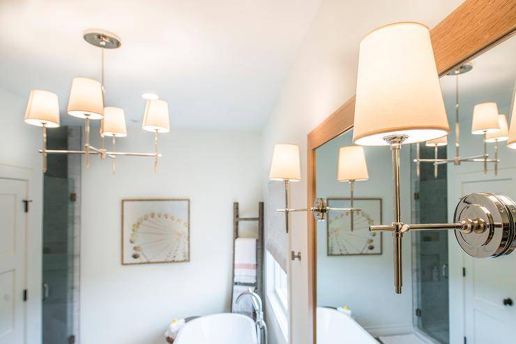 Master bathroom with shaded mirror and pendant lighting from Circa Lighting, a freestanding white tub, and a natural wood mirror over a custom vanity. Natural wood, blush, and navy all accent the white color scheme of the space.