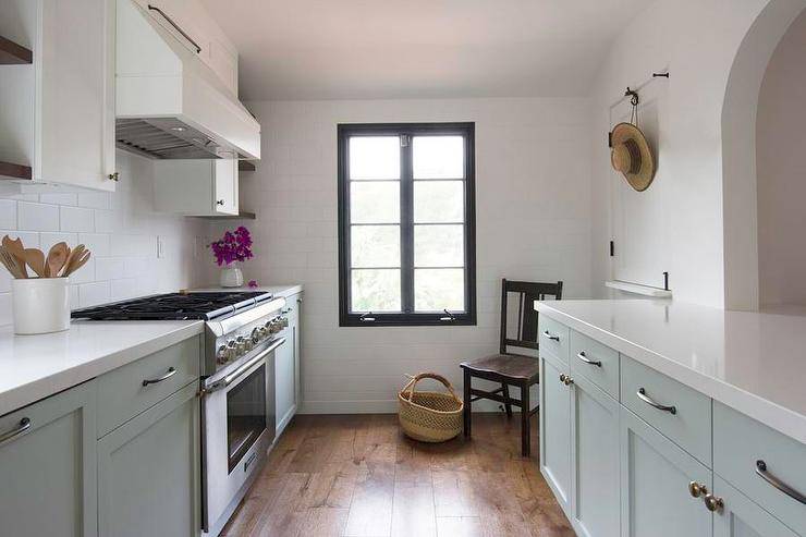 Gray galley style kitchen features gray cabinets with white backsplash subway tiles and oil rubbed bronze hardware. White quartz countertops keep a sleek surface for an updated kitchen aesthetic.