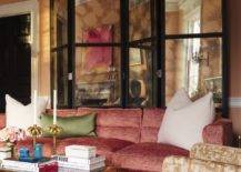 mirrored room divider behind pink fabric couch gold coffee table candlesticks white green throw pillows