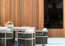 Restoration Hardware Capri Teak Armchairs sit at a gray outdoor dining table placed on concrete pavers framed by black river rocks.