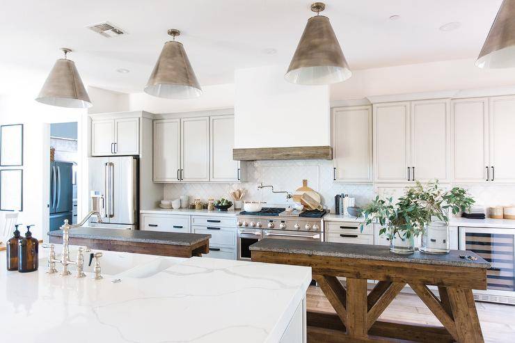 Side-by-side concrete and wood kitchen islands are illuminated by Goodman Hanging Lamps in a beautifully appointed cottage kitchen.