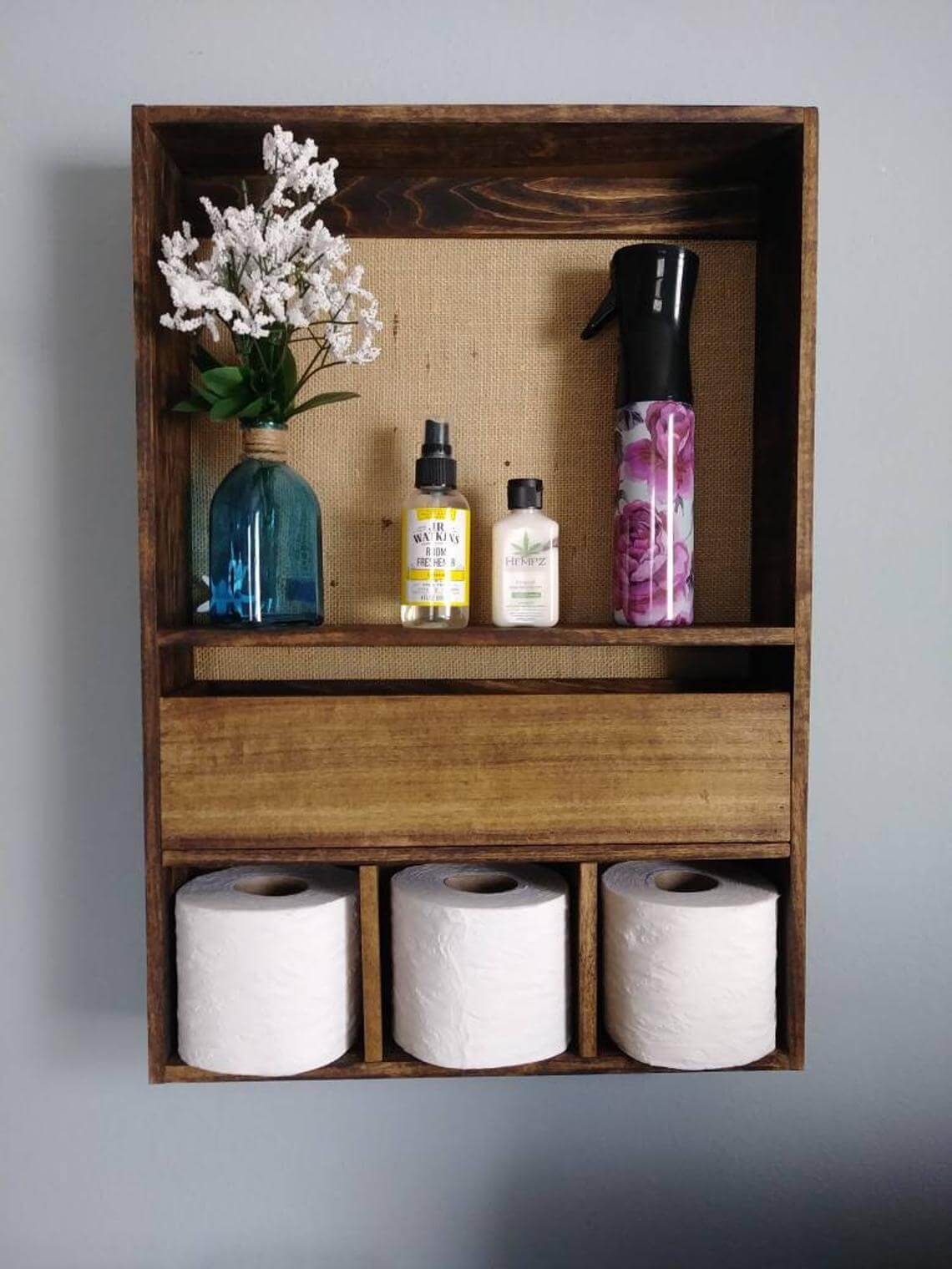 modern cubby over toilet storage shelf with rolls of toilet paper