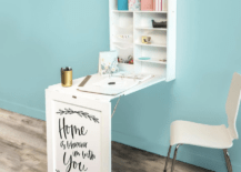 white fold down desk with inspirational saying on the front white chair in a room with baby blue wall and wood flooring