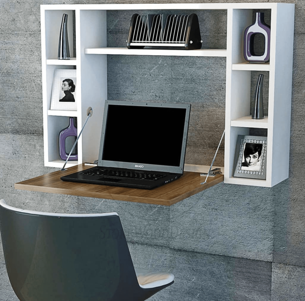 white fold down desk with cube style open shelves attached to wall with laptop picture frame deco vases