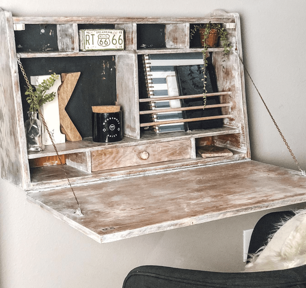 rustic painted fold down desk mounted on to the wall with books decor and a chair with fur pillow