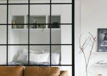 large steel and glass room divider behind brown leather couch black and white living room