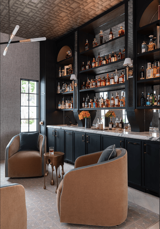 black wet bar with club chairs in front marble countertop tall shelves with liquor