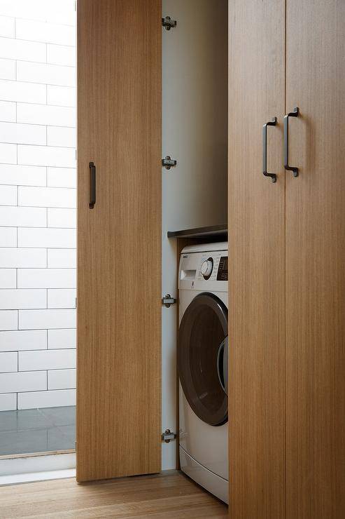 A modern closet with bi fold doors open to a front load washer and dryer.