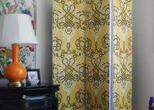 yellow pattern fabric room divider white wall room with black dresser and orange lamp