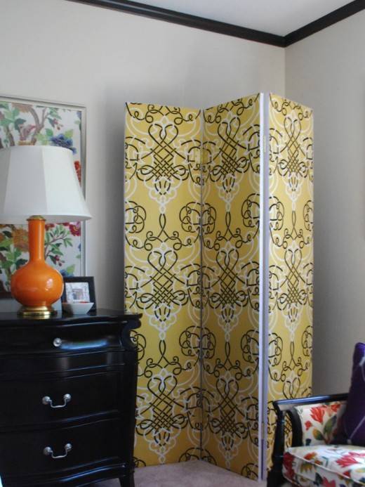 yellow pattern fabric room divider white wall room with black dresser and orange lamp