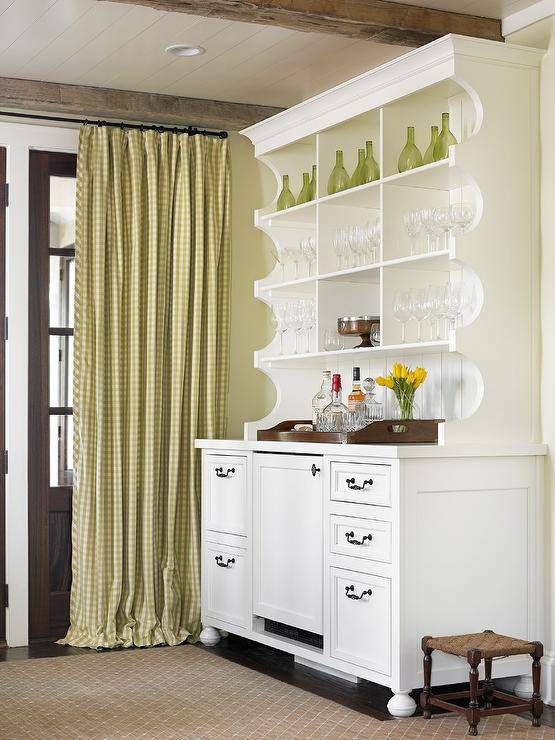 Cottage kitchen features a white sideboard and scalloped hutch with oil rubbed bronze pulls and green gingham curtains.