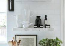 Marble floating shelves are stacked against white subway backsplash tiles and over a marble countertop.