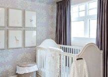 White and purple nursery features a white French arch nursery crib on a gray trellis rug, an art gallery on purple medallion wallpaper, woven baskets and purple silk curtains.