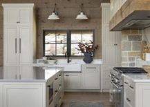 Country kitchen features kitchen island with zinc top, a stone clad cooking alcove with spice shelf on a marble look cooktop backsplash and white cabinets.