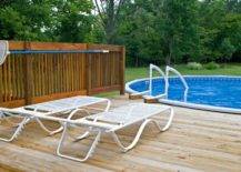 above ground pool with deck and two white lounge chairs