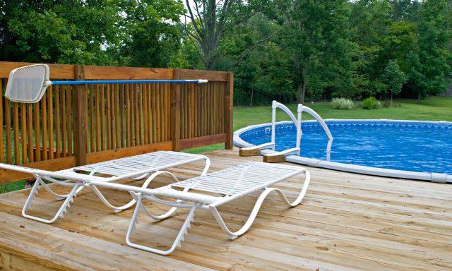 above ground pool with deck and two white lounge chairs