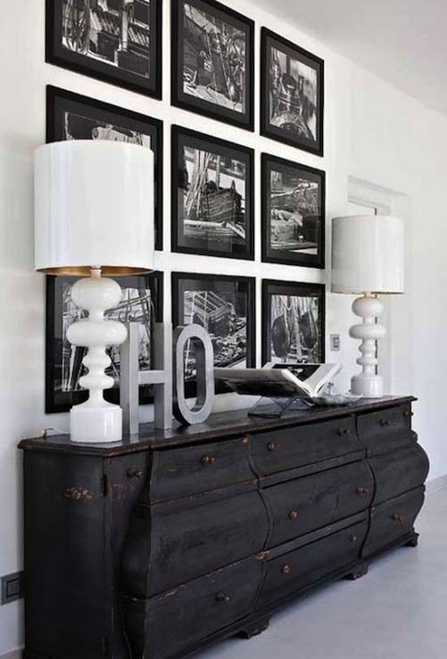 Amazing foyer design with distressed credenza, glossy white lamps and white & black photo wall gallery.