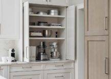 Kitchen features a small appliance cabinet with white folding doors and drawers accented with nickel pulls.