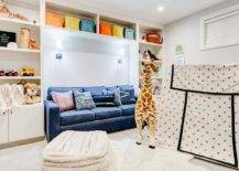 basement kids area with couch large giraffe stuffed animal white cube shelves