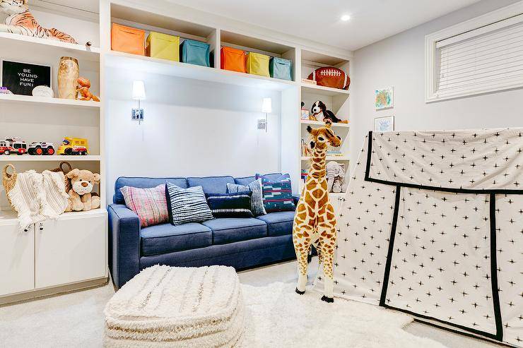 basement kids area with couch large giraffe stuffed animal white cube shelves