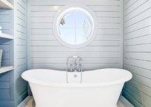 Bathroom features a white roll top bathtub in a blue shiplap nook that boasts a blue shiplap barrel ceiling, blue shiplap walls and staggered marble floors.