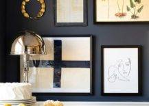 A black dining room wall is accented with an eclectic art gallery hung over white wainscoting.