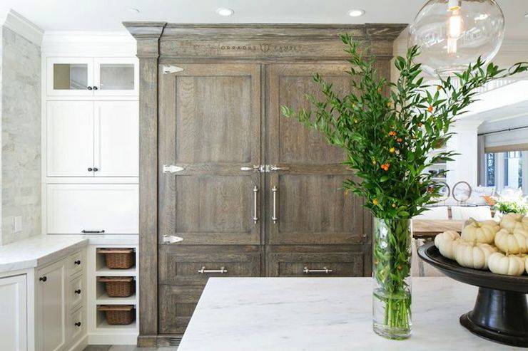 White and gray kitchen features a built-in refrigerator and freezer drawers concealed behind gray wash cabinet doors and drawers beside white built-in cabinets tacked over lift-up appliance garage over vertical cubbies filled with pull-out baskets.