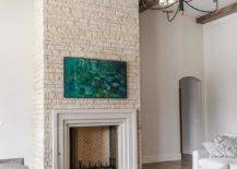 A Samsung Picture Frame TV is mounted to an ivory stone fireplace wall over an art deco style beveled mantel.