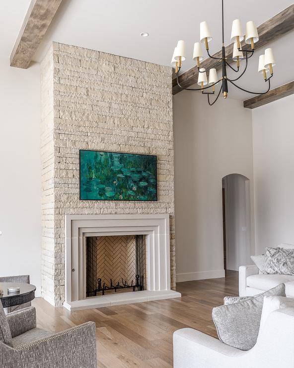 A Samsung Picture Frame TV is mounted to an ivory stone fireplace wall over an art deco style beveled mantel.