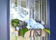 decorative planter box with faux flowers house numbers hanging from blue front door