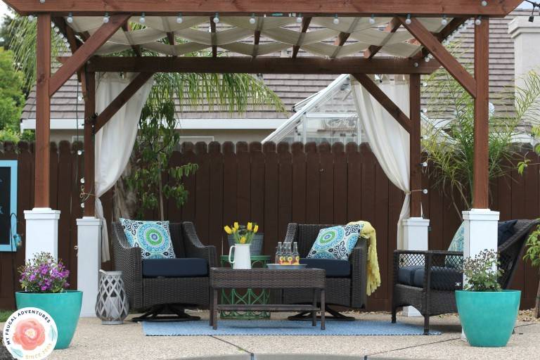 wide shot of pergola in backyard with patio furniture and turquoise blue pots