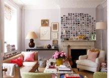 Eclectic living room design with white branch floor lamp, white sofa, black glass console table, maroon gourd lamp, pink pillows, Polaroid photo wall gallery, marble fireplace and soft lilac walls paint color.