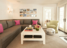 Gorgeous living room boasts a photo collage over a dark gray sectional adorned with hot pink across from a white lacquered coffee table with shelf alongside a yellow and green accent chair paired with a silver Moroccan pouf atop a diamond jute rug.