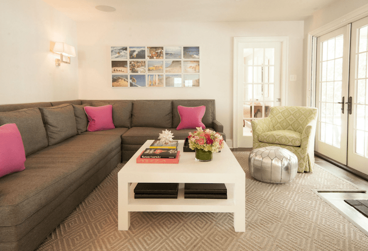 Gorgeous living room boasts a photo collage over a dark gray sectional adorned with hot pink across from a white lacquered coffee table with shelf alongside a yellow and green accent chair paired with a silver Moroccan pouf atop a diamond jute rug.