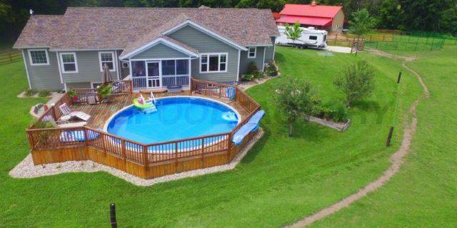 full deck around above ground pool behind house in backyard