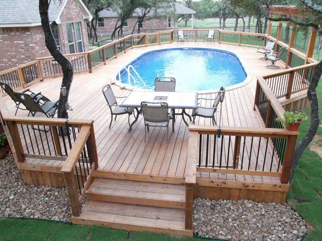 above ground pool framed in by large wood deck with seating and eating area patio furniture