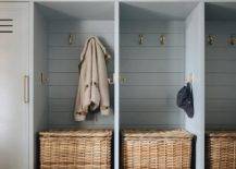 Mudroom features gray lockers with brass hooks on gray shiplap trim, brown drawers and cubbies with woven baskets.