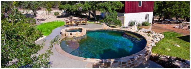 hillside above ground pool with barn in background with stone wall