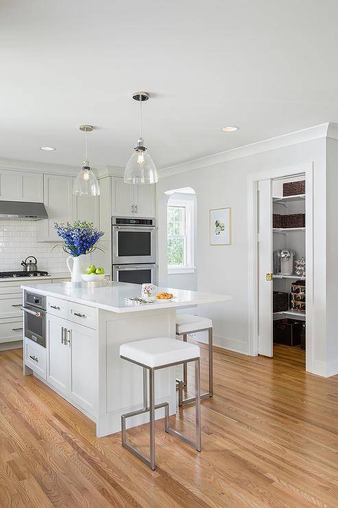 A kitchen pantry with pocket doors and brass hardware open up to added space and stacked shelves offering storage in the utmost organized way.