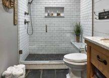 white subway tile farmhouse basement bathroom with wood vanity toilet grey slate floor tobacco basket hanging on wall basket of rolled towels